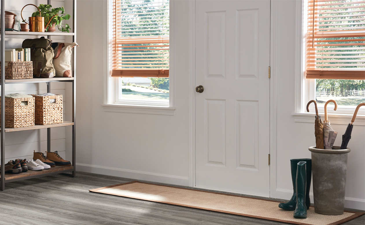 wood blinds at front door in home with gray wood flooring